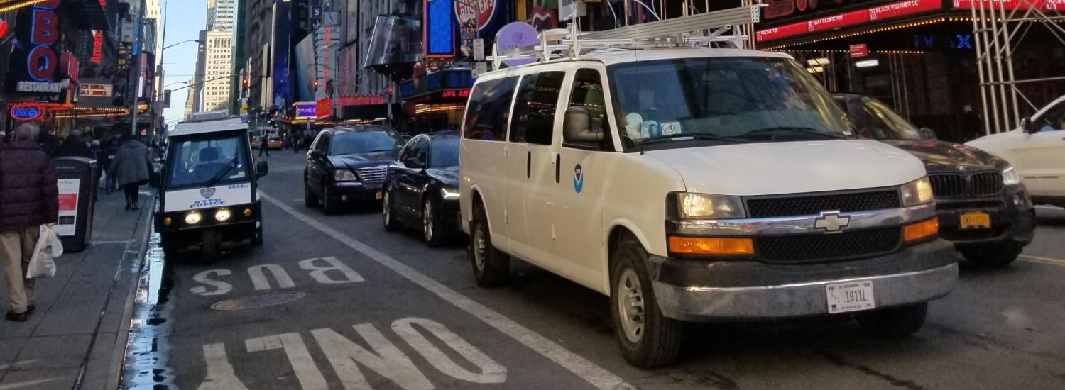 A van drives through New York City traffic. 