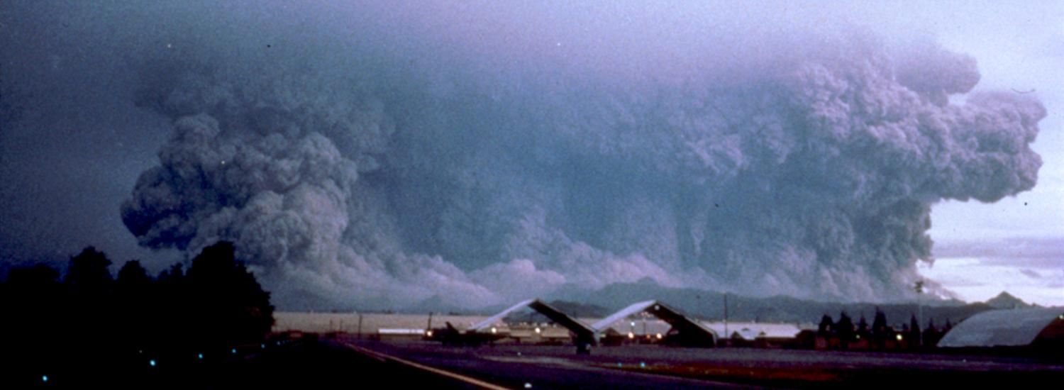 Volcano erupting, sending ash and other material into the air as a large, dark cloud.