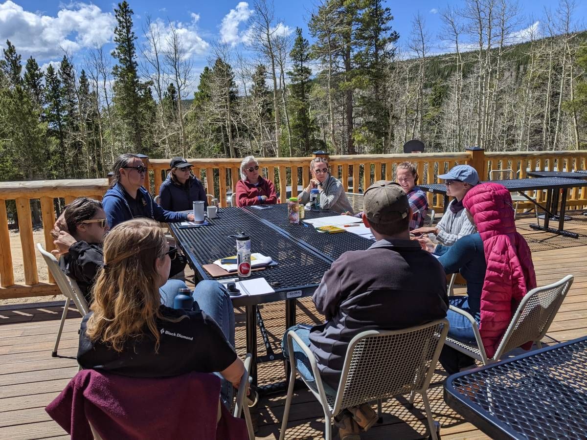 A GROUP OF PARTICIPANTS DICUSS PROPOSAL IDEAS OUTSIDE AT THE MOUNTAIN RESEARCH STATION