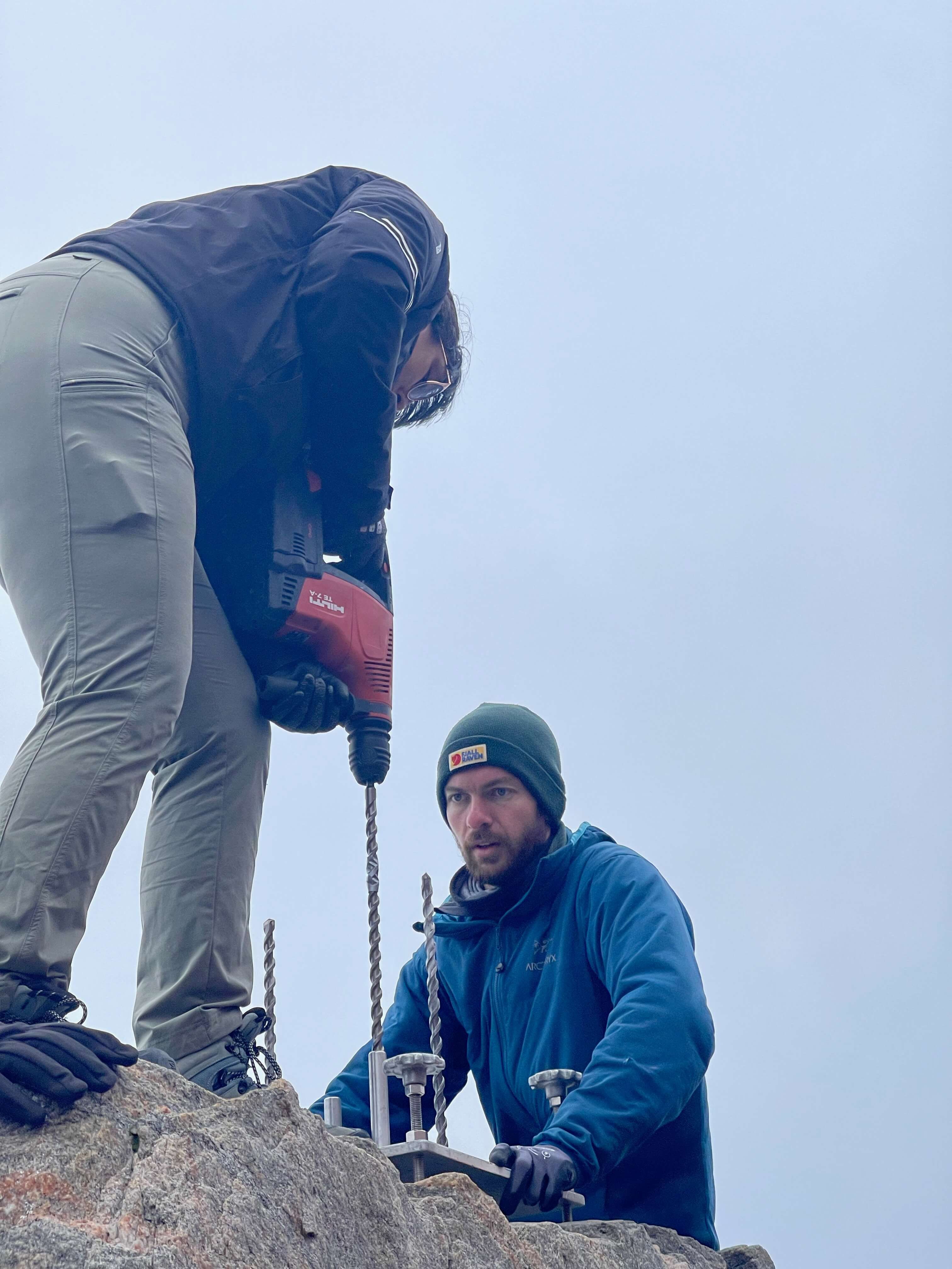 two people with tools on a rock