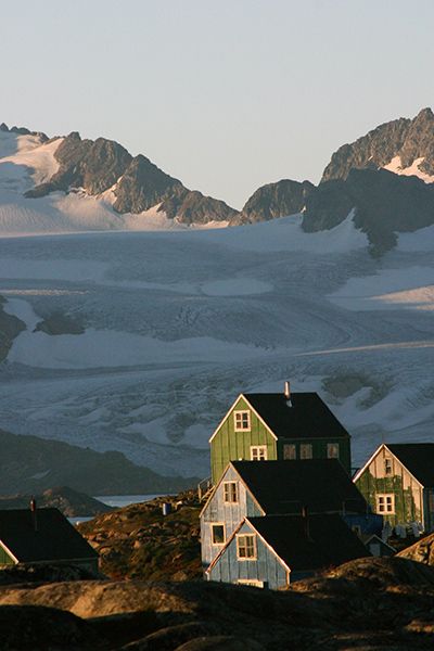 House lit in the setting sun with snow covered mountains behind them