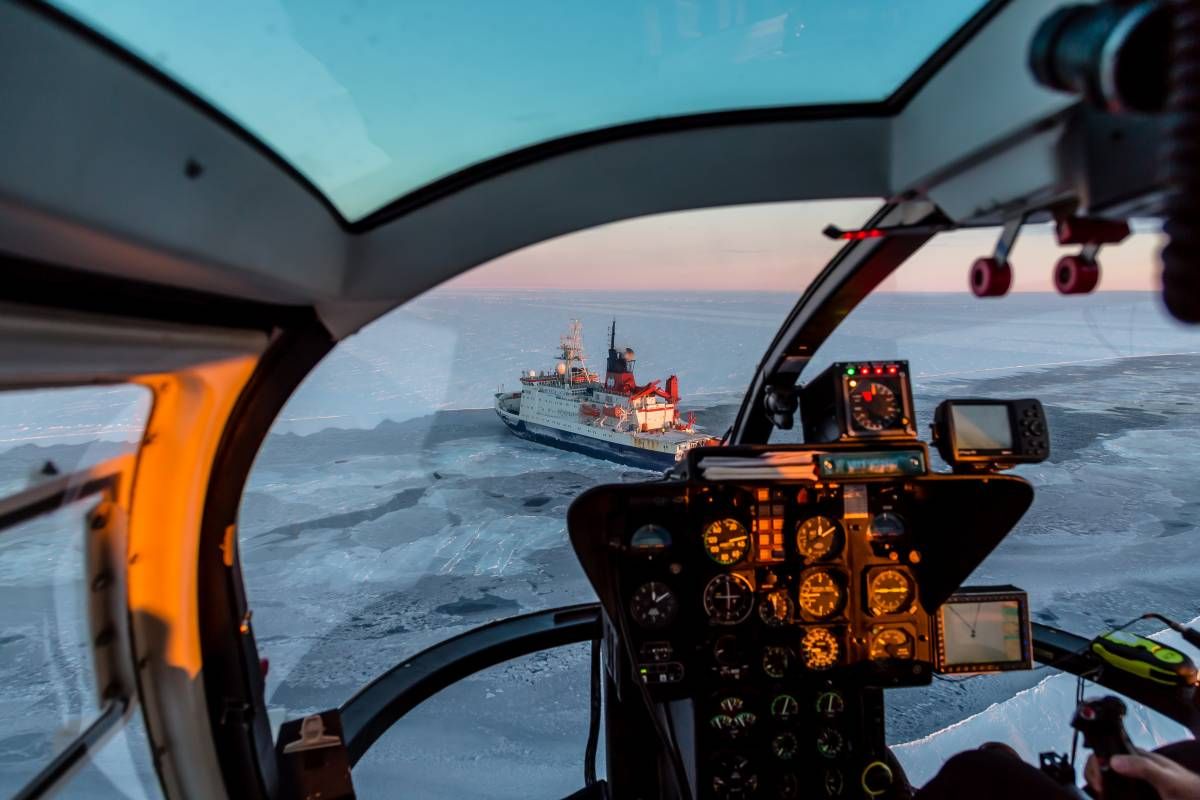 Shot of a helicopter cockpit flying above ice. 