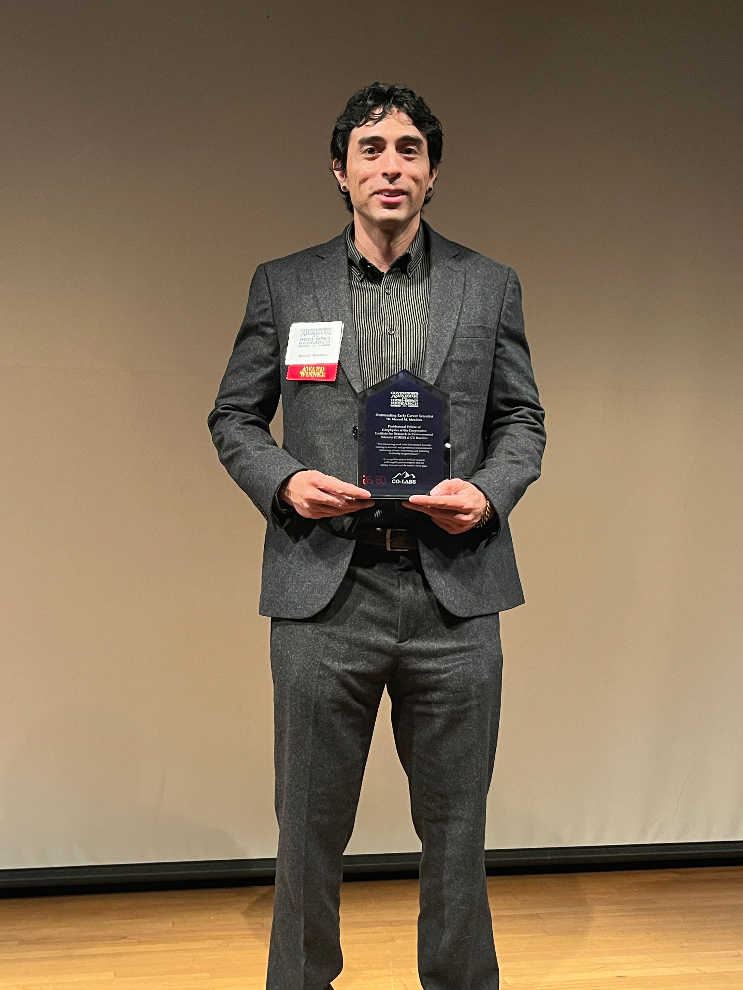 Matt Mendoza stands onstage with his Governors Award