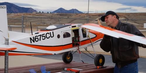 A man inspects a unmanned aircraft system, which is white and orange in color