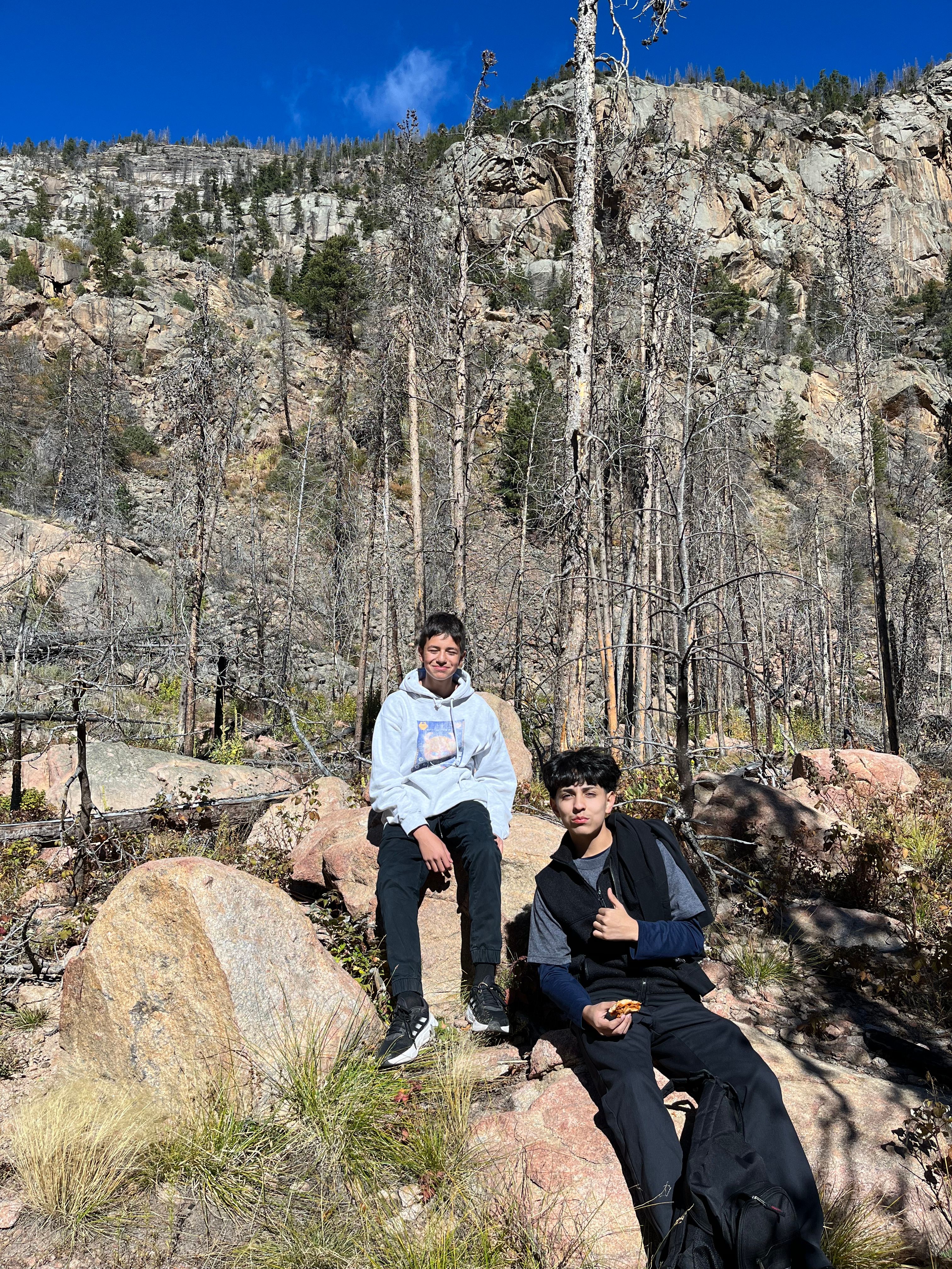 Two STEM Launch students sit on a boulder for a lunch break in RMNP