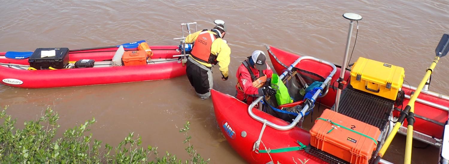 two researchers wade next to inflatable rafts carrying monitoring equipment