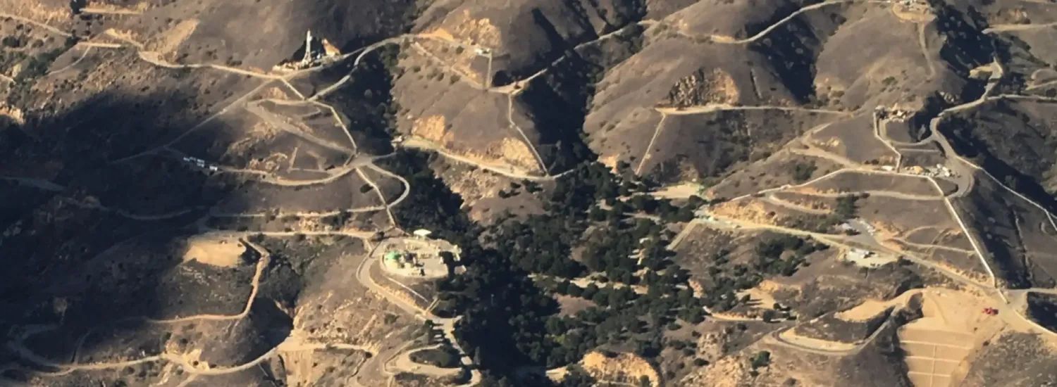 Aerial photo of a building in a hill shrubbery landscape 
