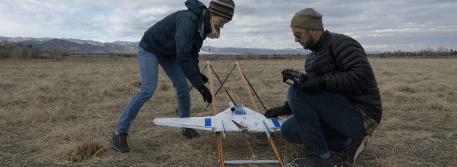 Two people place a DataHawk drone on its launcher in preparation for its first test flight in Boulder, Colorado.