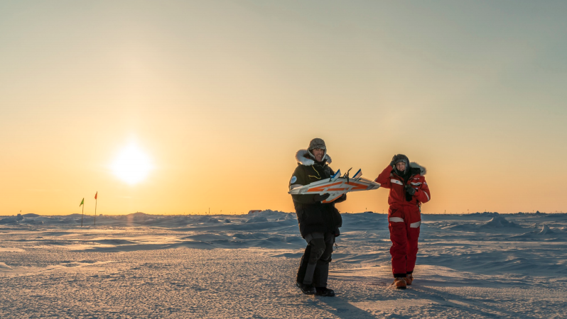 MOSAiC scientists holding an unmanned aerial aircraft in the Arctic.