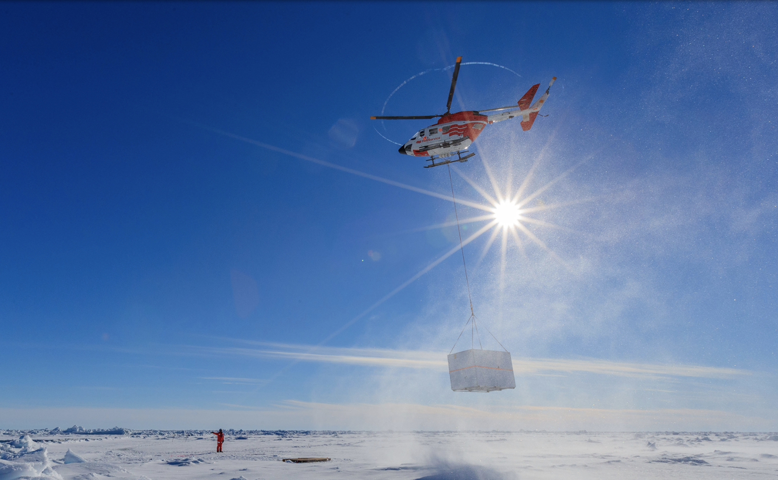 A helicopter is used to move heavy equipment around the ice.