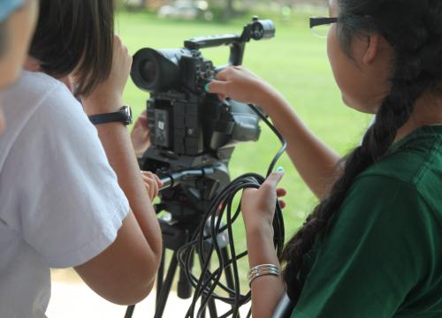 students gather around video equipment