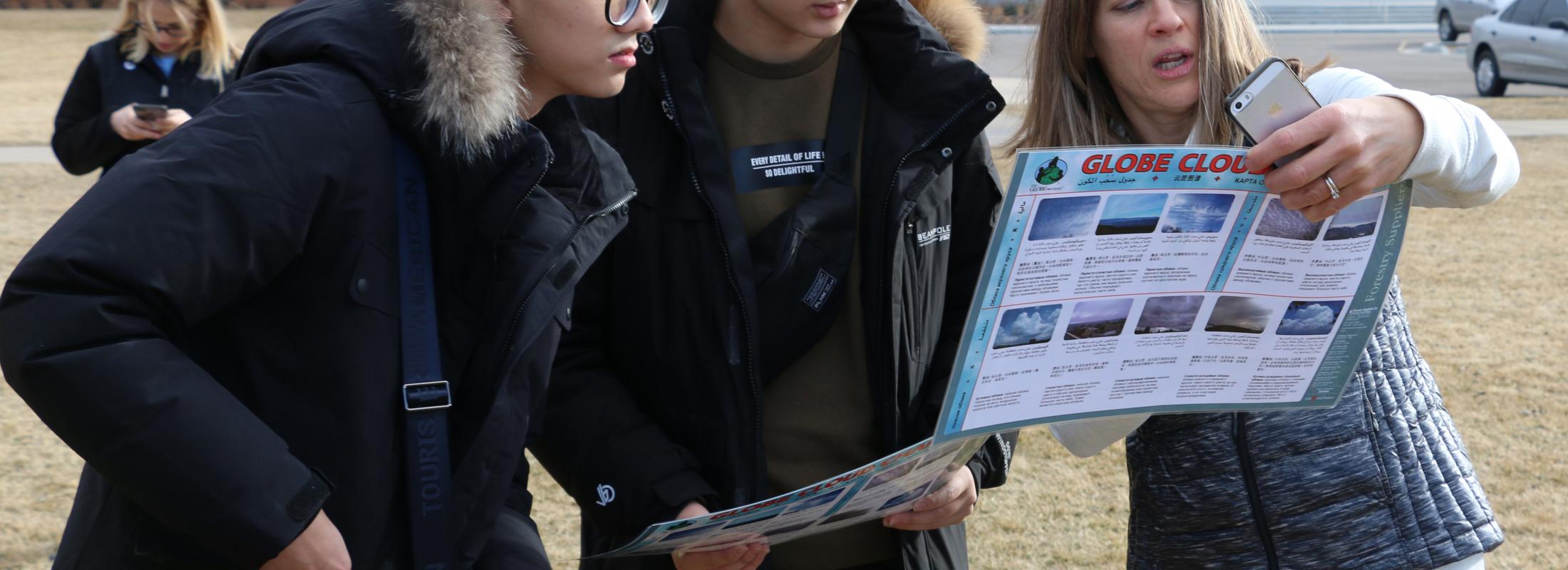 Chinese students look at chart held by an instructor outdoors
