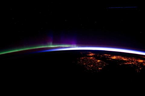 NOAA image of Earth's horizon from space you can see a green light on one side and a blue light on the other side of the horizon and some cities lit up from space on the Earth