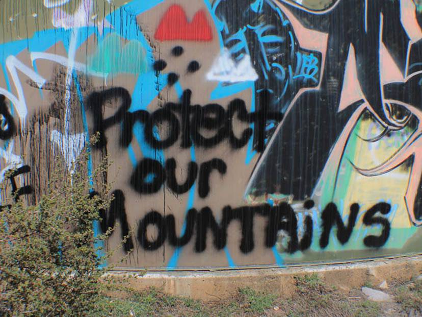 Graffiti on wall above a hill in Tsaile, AZ. Reading "Protect our Mountains". 