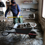Shoveling mud out of the store room in Scotty's Castle Visitor Center. NPS.